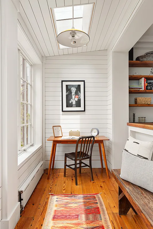 porch off kitchen with a skylight, white walls and a wood floor