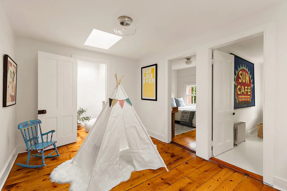 the upstairs hallway with wide plank floorboards, white walls and doors to bedrooms