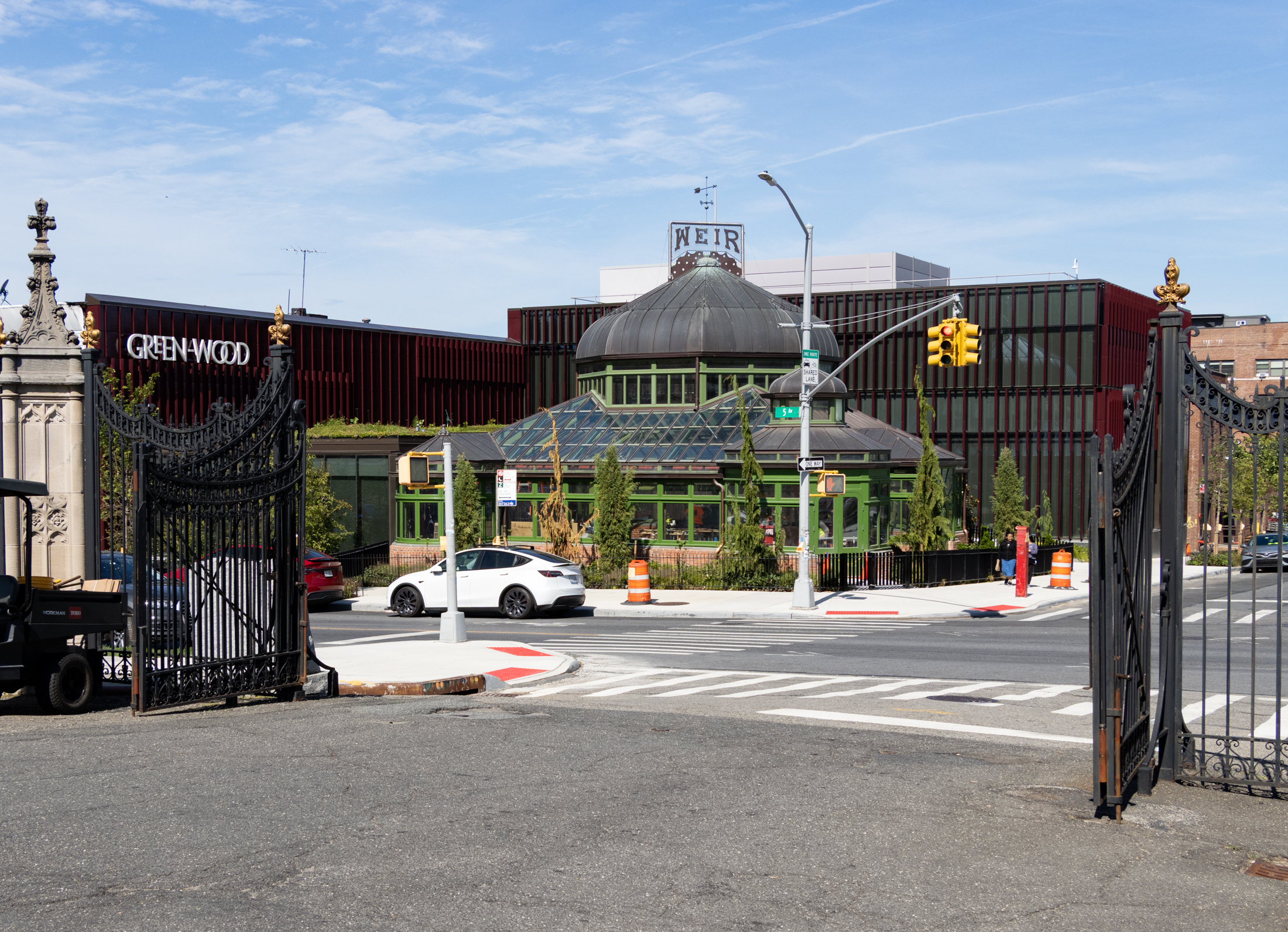 view from inside the cemetery gates with restored greenhouse across the street with wings of new buildings