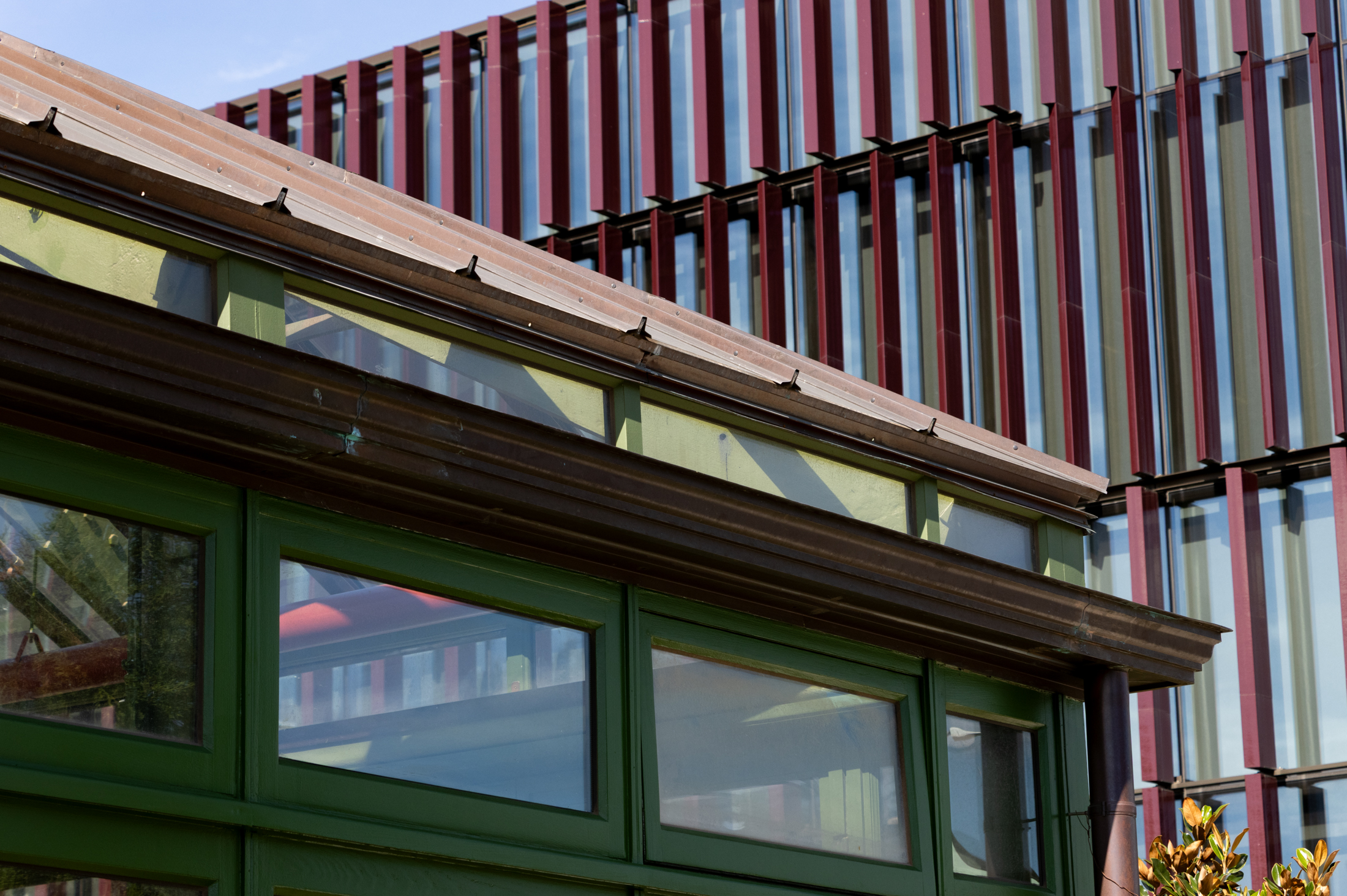 the greenhouse with the terra cotta slats of the new building behind