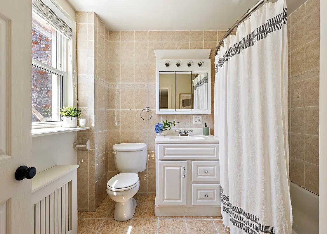bathroom with beige wall and floor tile, white fixtures