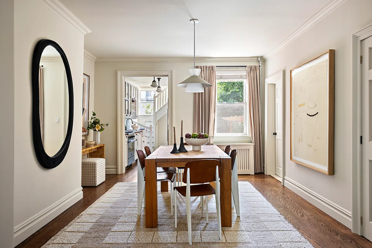dining room with wood floor, cream walls, view to the kitchen beyond