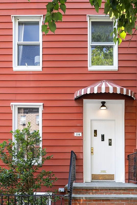exterior with red siding and a red and white striped awning above the door