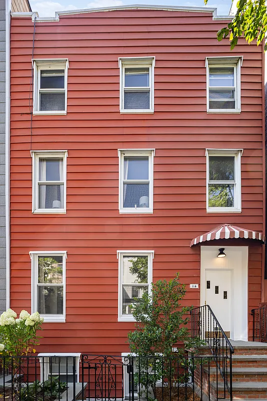 exterior with red siding and a red and white striped awning above the door