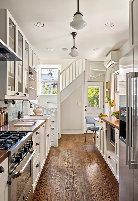 kitchen with white cabinets, butcher block counters, and apron front sink and a staircase leading upstairs