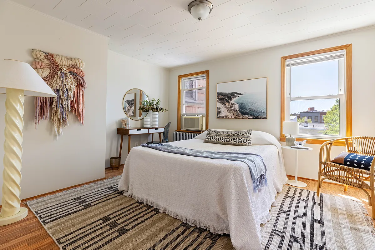 a bedroom with two windows, wood floor