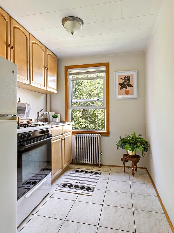windowed kitchen with tile floor, wood cabinets
