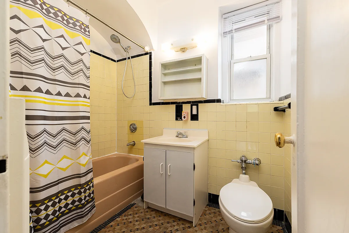 bathroom with yellow and black wall tile and a peach tub