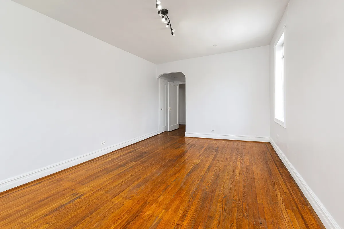 bedroom with wood floor and arched doorway to closet