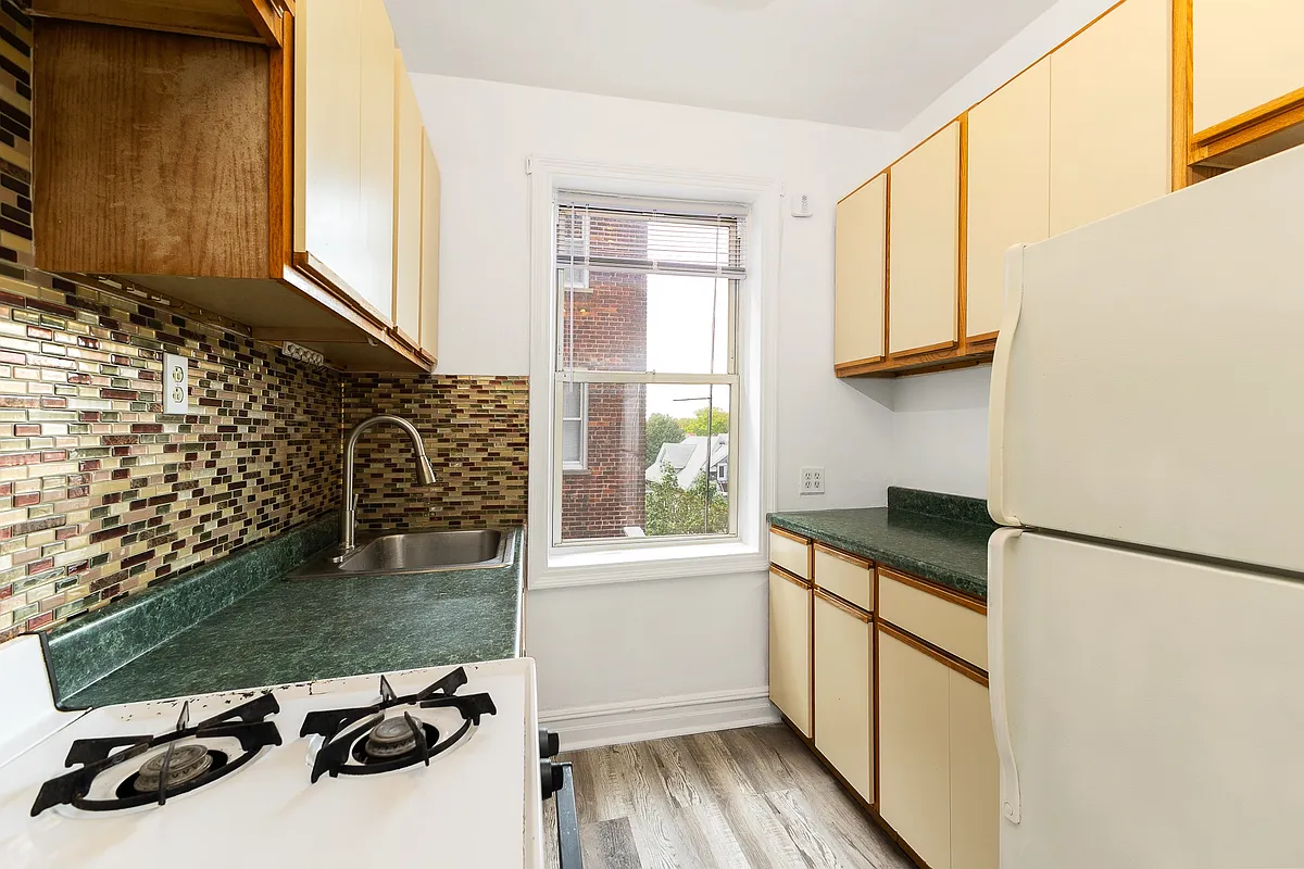 kitchen with laminate and wood cabinets, faux wood floor and a brown glass tile backsplash