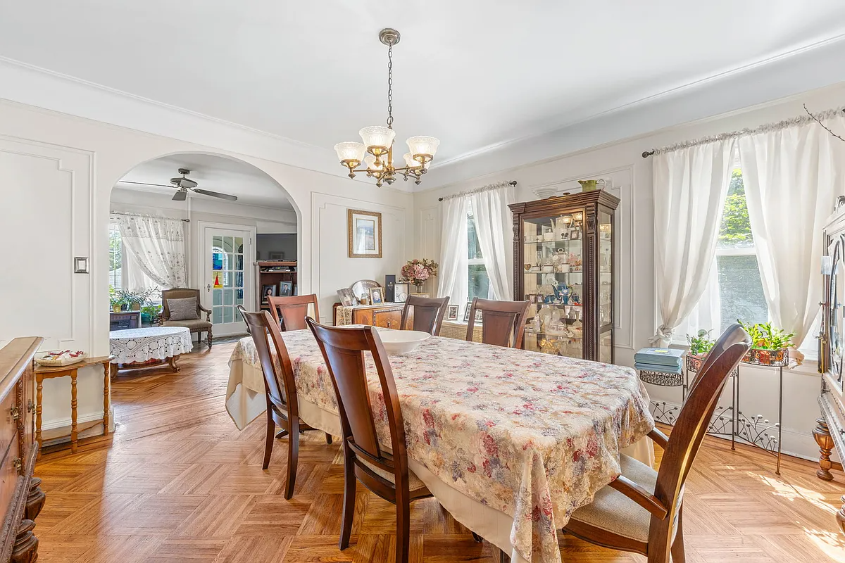 a dining room with wall moldings and an arched doorway