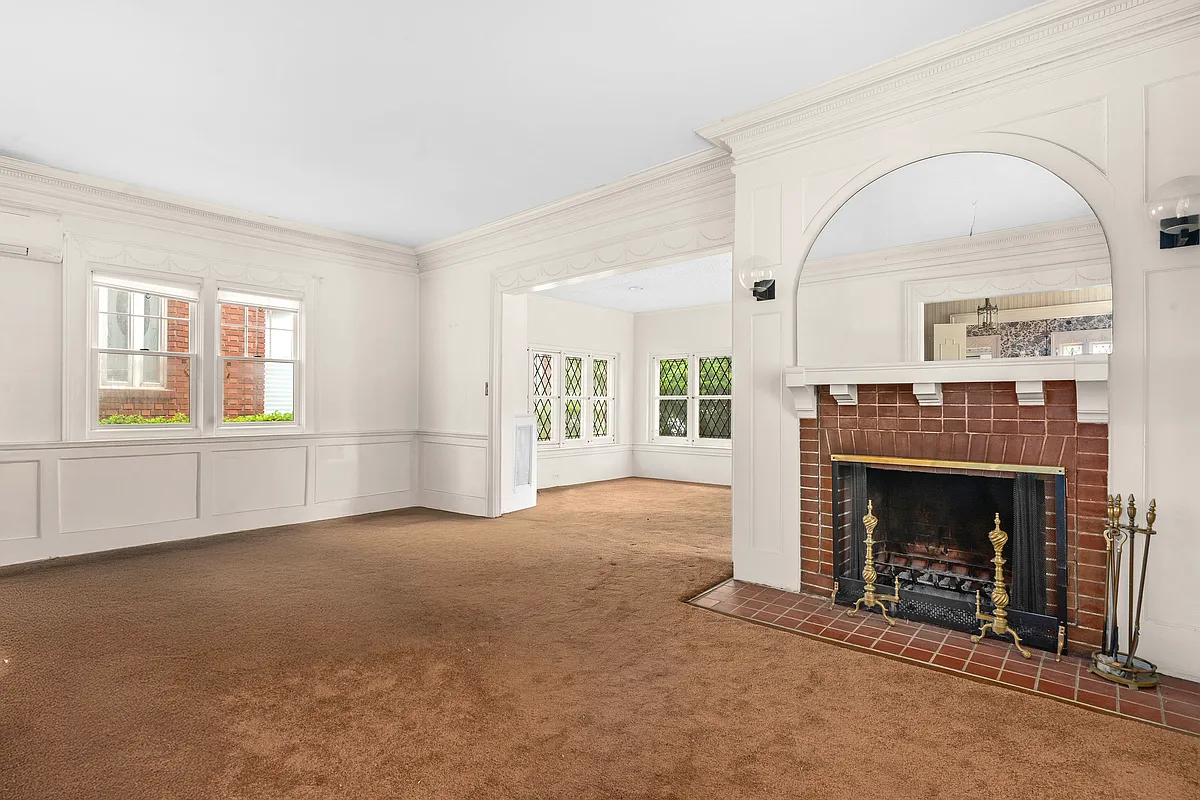 living room with carpet, fireplace with brick surround, wainscoting
