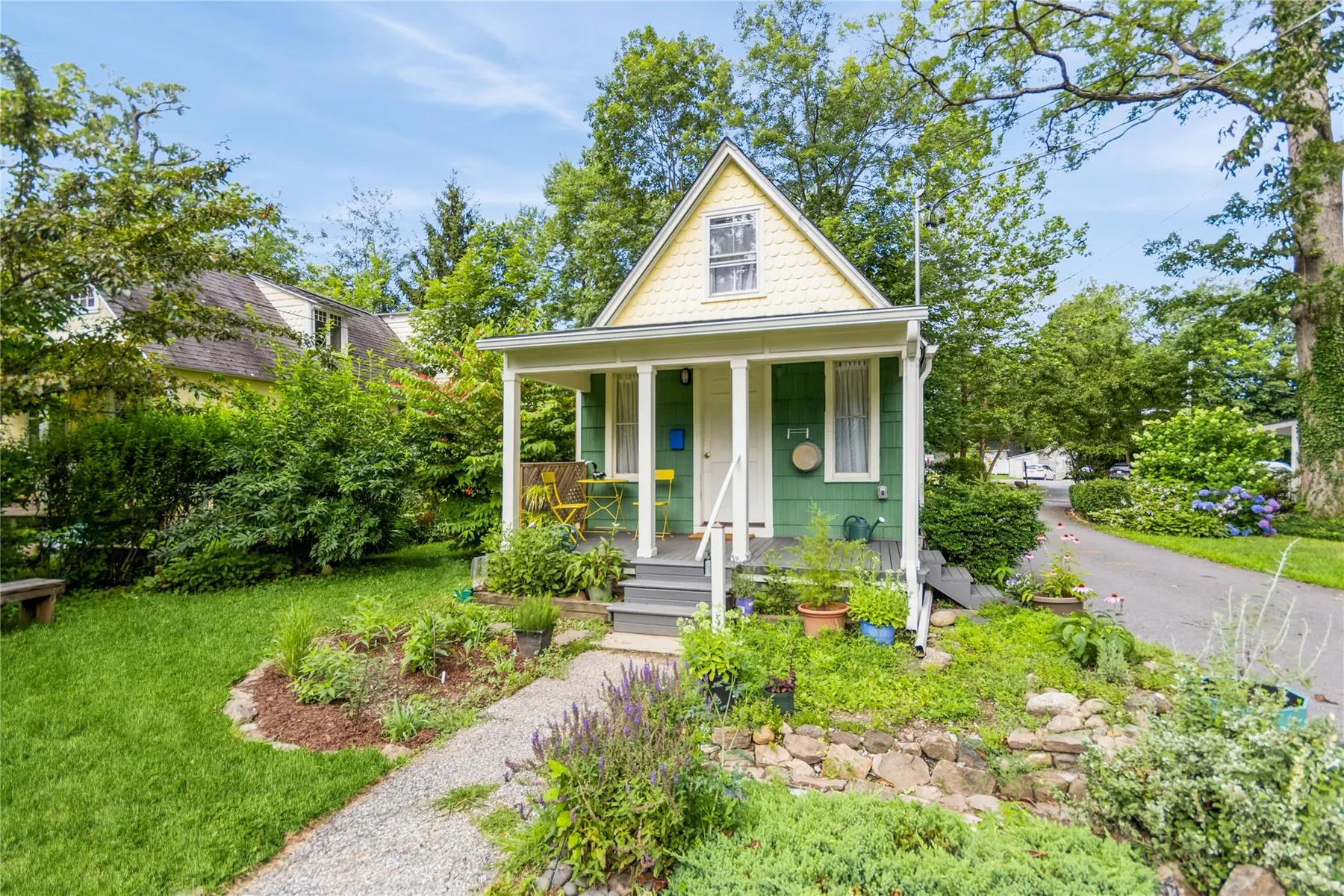 green cottage with a small porch and a yellow painted gable