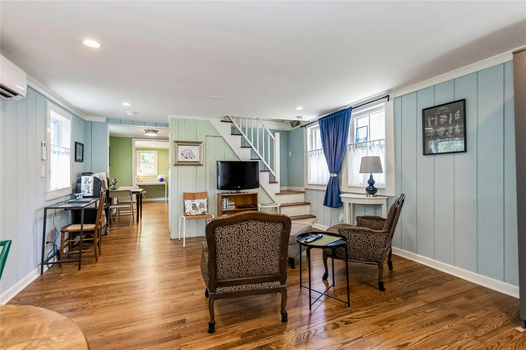 living room with wood floor, blue walls and a staircase