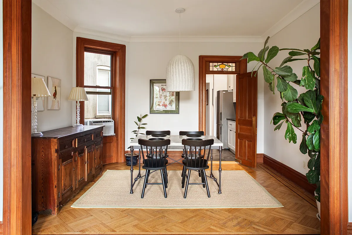 dining room with wood floor and a door to the kitchen with a stained glass transom