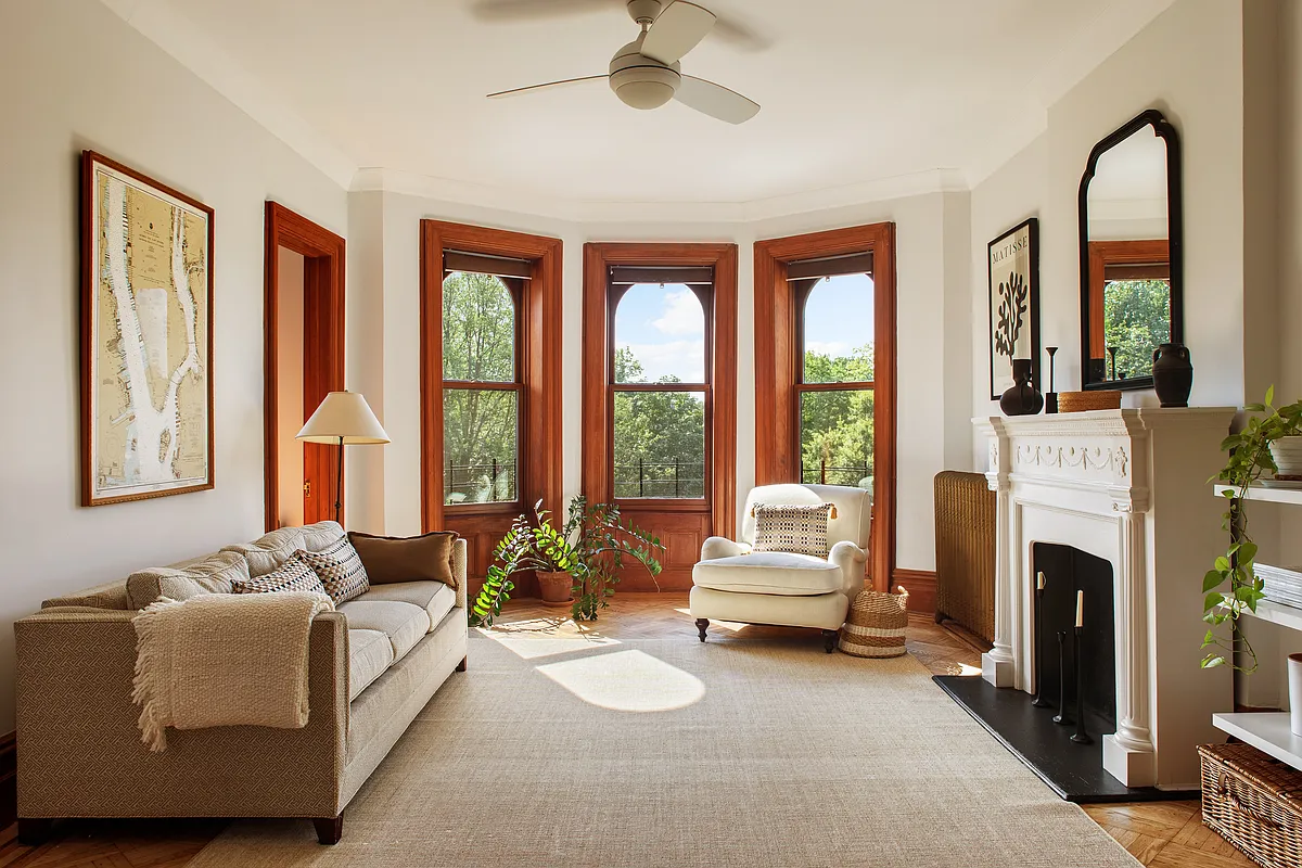 living room with bay window, mantel, ceiling fan