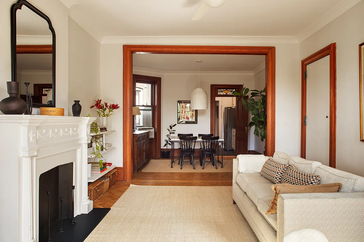 living room with mantel, wood trimmed doorway leading to dining room