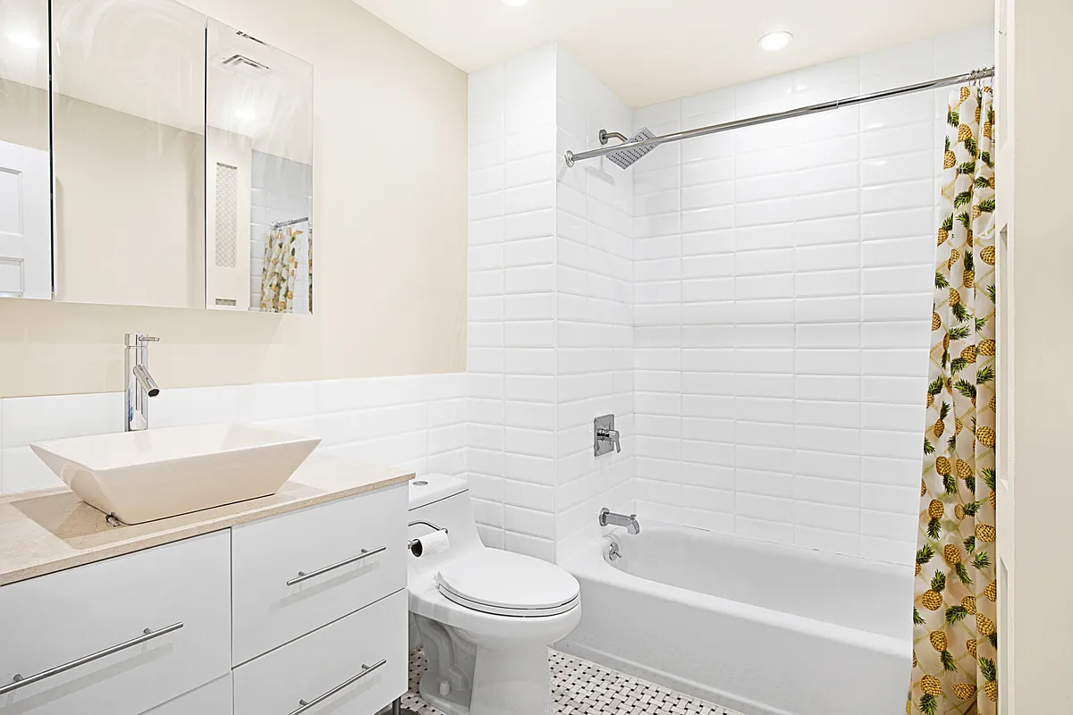bathroom with white fixtures and tile and a vessel sink