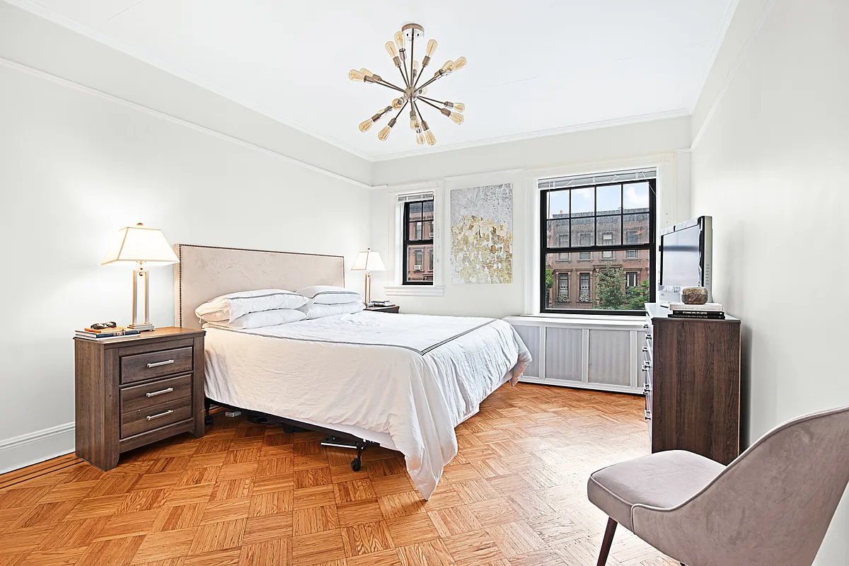 a bedroom with wood floor, white walls, picture rail