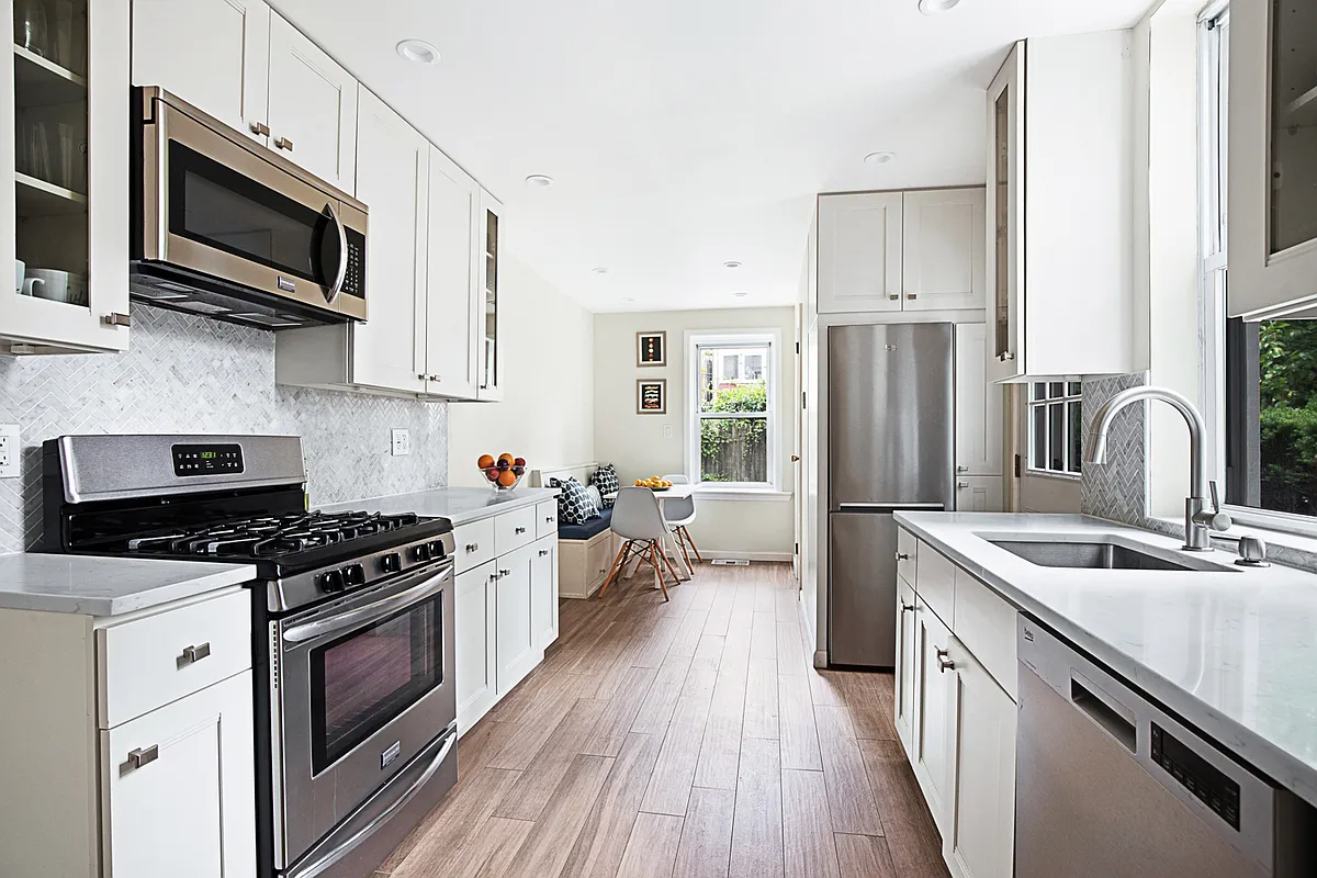 a kitchen with faux wood floor, white cabinets and a banquette