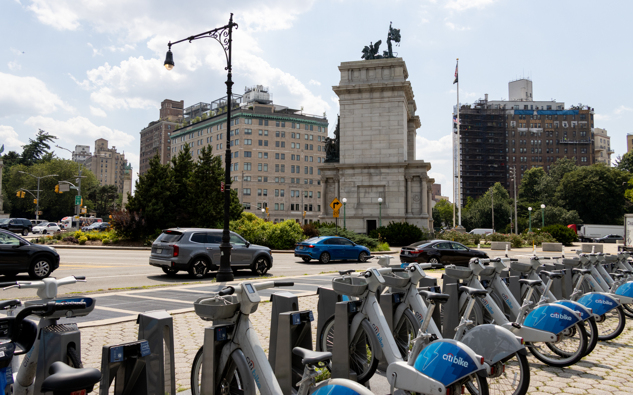 cars driving in grand army plaza with a banking station for citibikes in the foreground