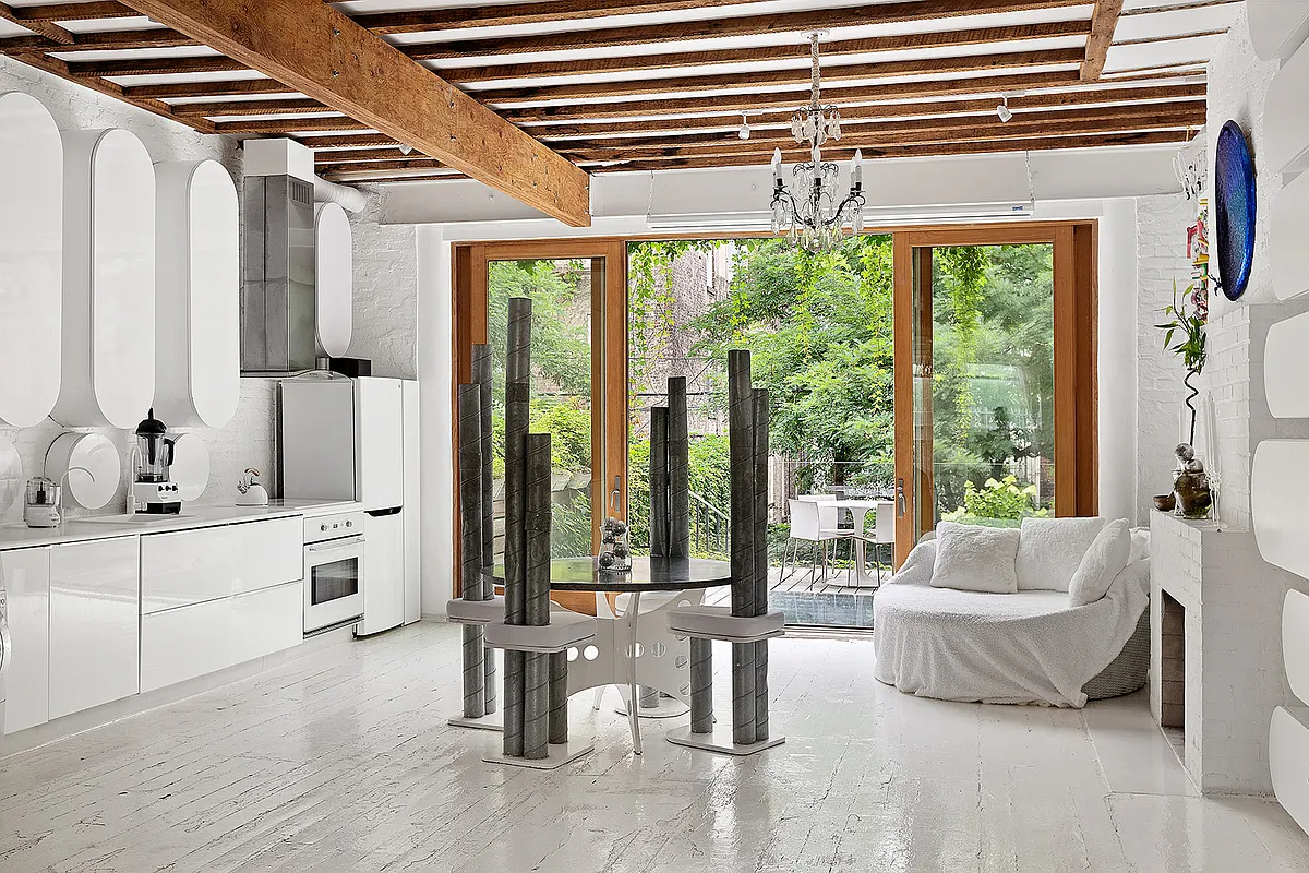 a white interior with a wall of glass leading to a garden