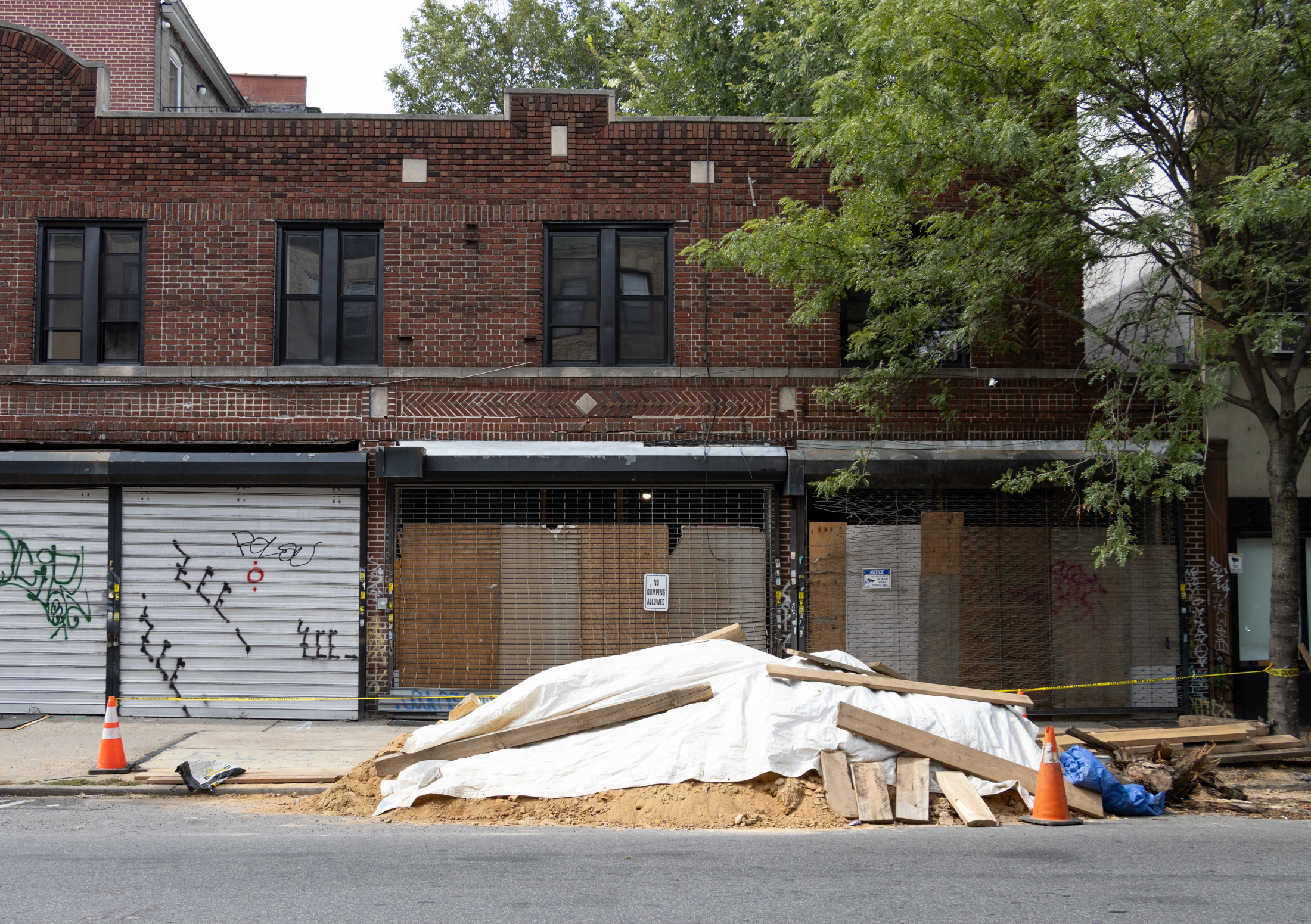pile of sand in front of the gates on the storefronts of a brick building