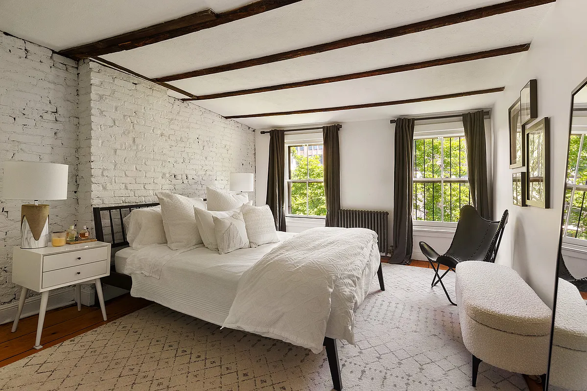 bedroom with exposed brick wall painted white, exposed rafters