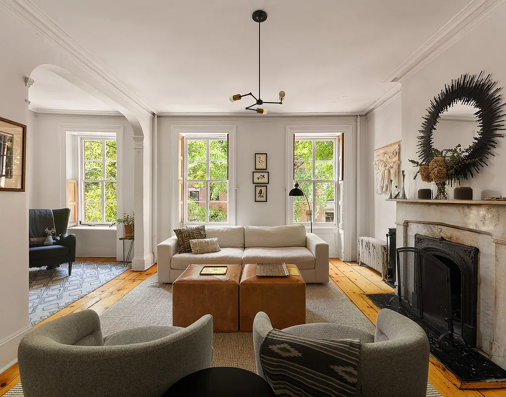 a living room with wide plank floor boards and a marble mantel