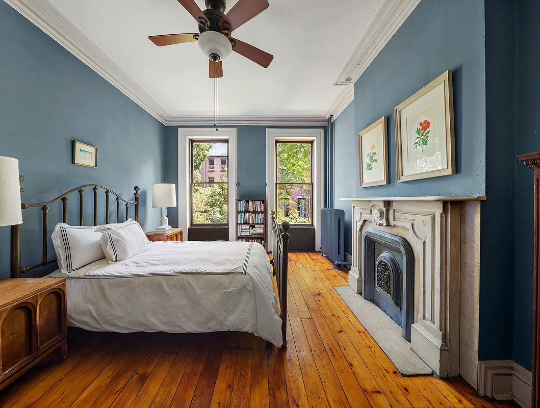 bedroom with blue painted walls, a marble mantel, and a ceiling fan