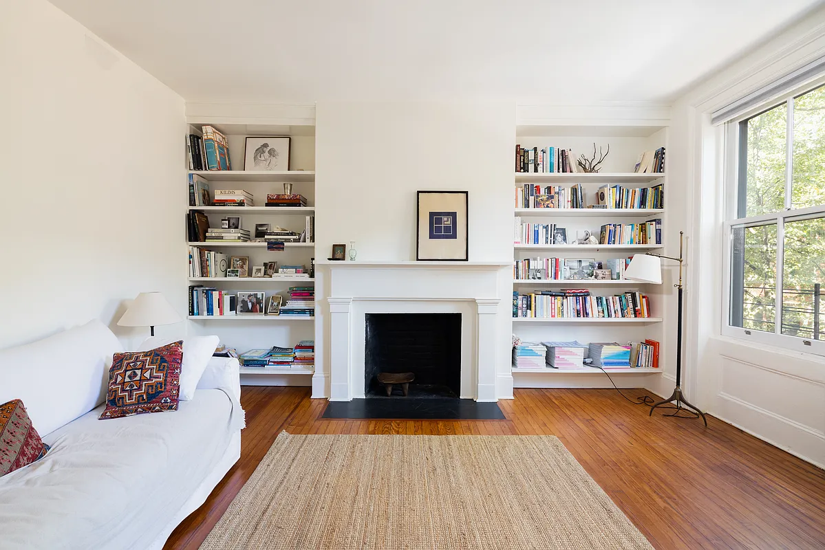 bedroom set up as a den with wood floor, built-in bookshelves on either side of a mantel