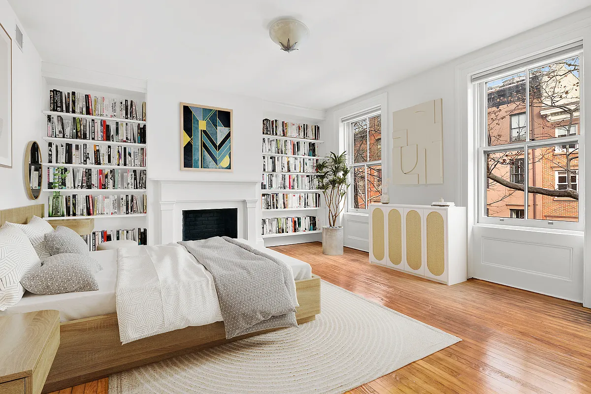 virtually staged bedroom with a white mantel, wood floor, two windows