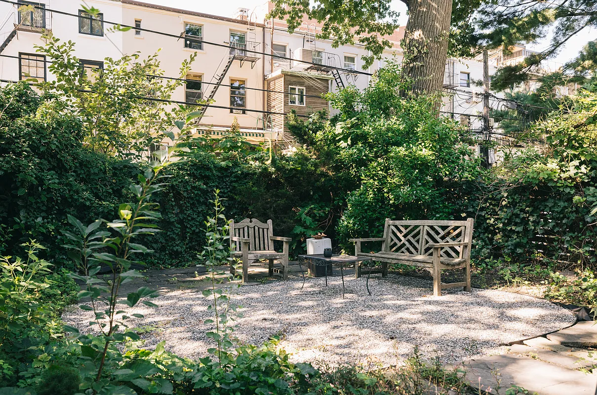 garden with gravel covered seating area surrounded by greenery