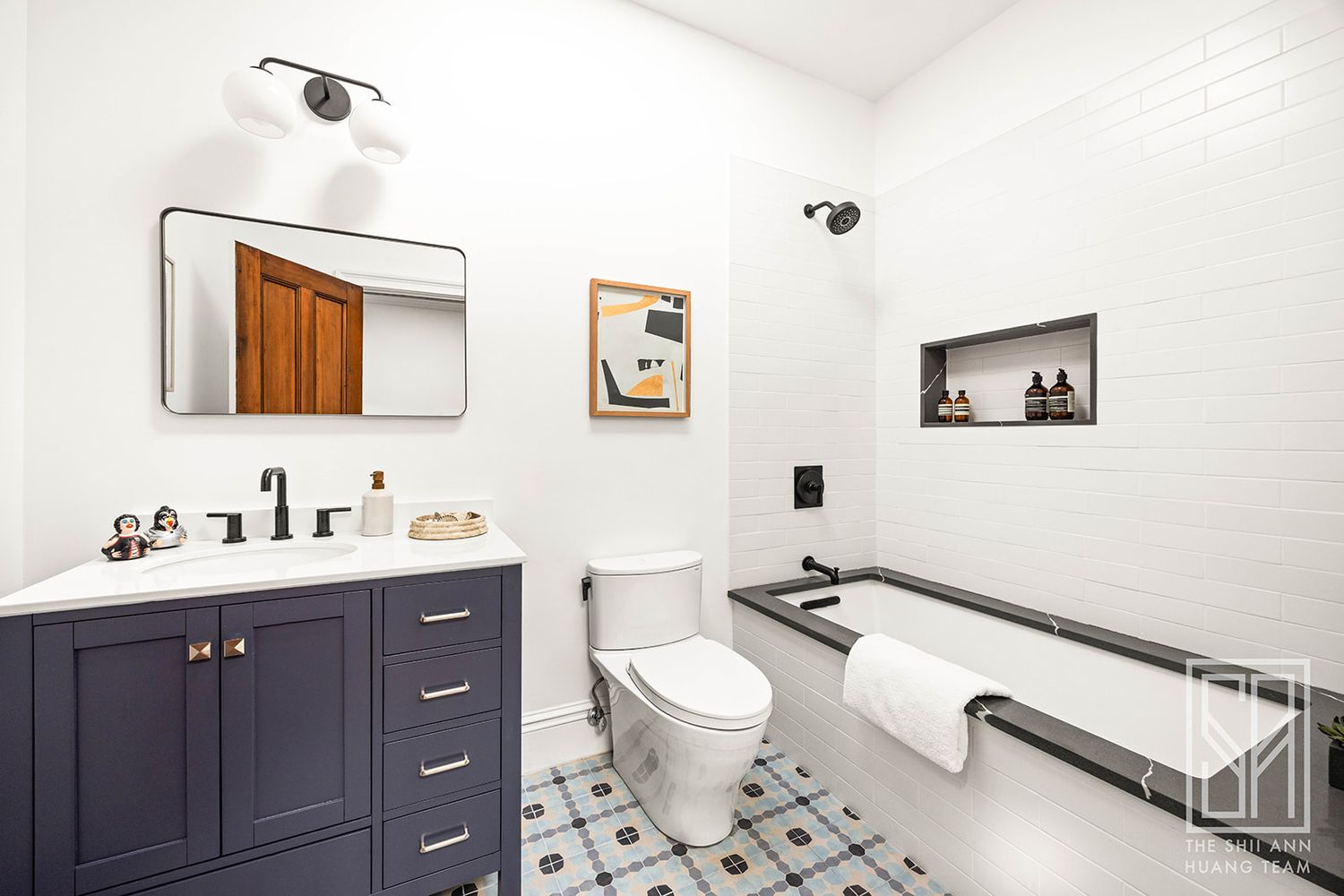 bathroom with soaking tub, patterned tile floor, blue vanity