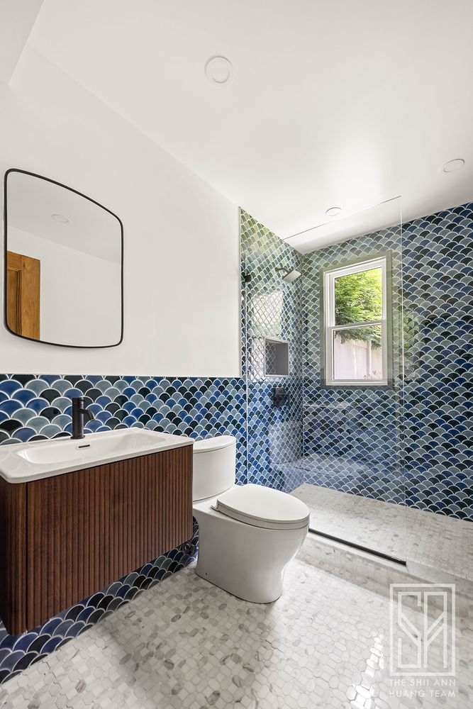 garden level bathroom with blue tiles on walls, a walk-in shower and a floating vanity