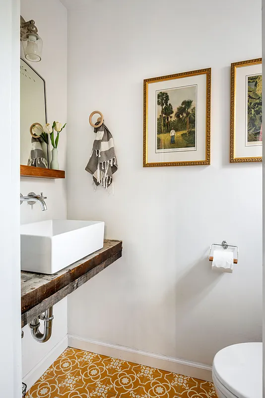 half bath with graphic floor tile, white vessel sink mounted on a slab of wood