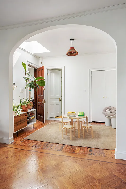top floor skylit room with wood floors, white walls