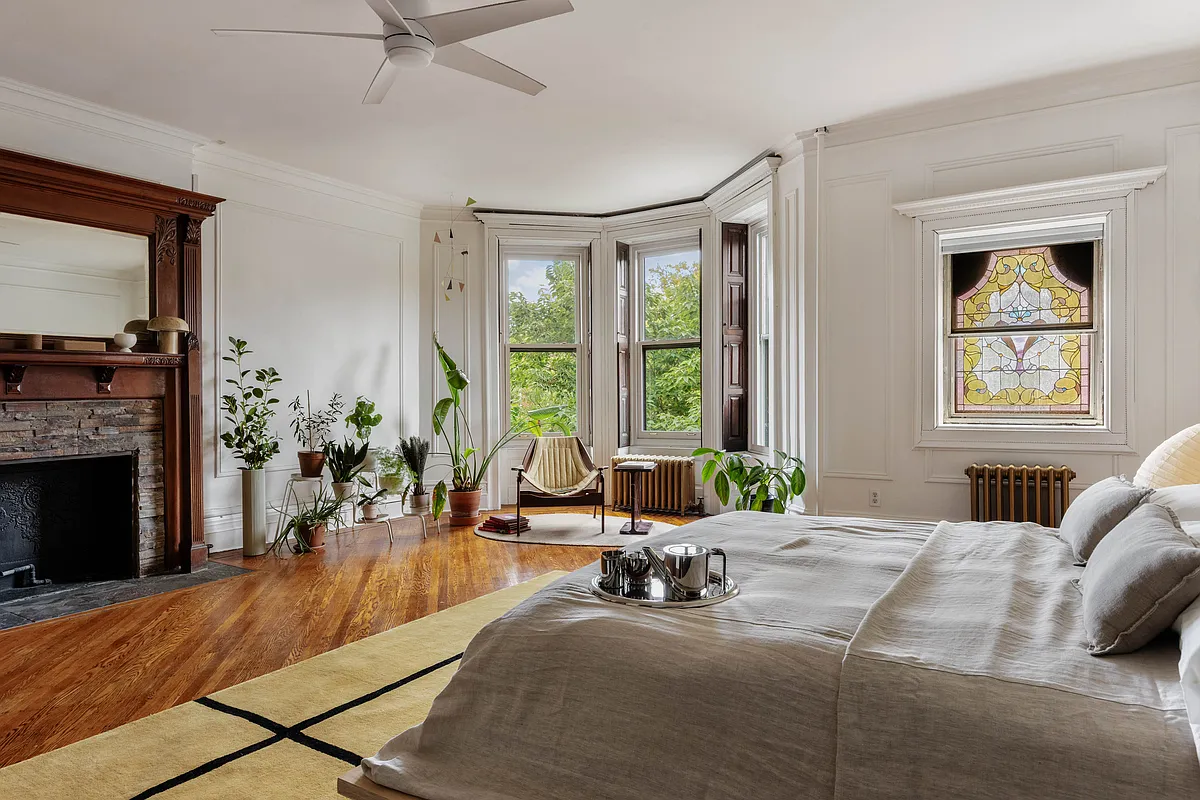 bedroom with stained glass window, wood floor, wood mantel