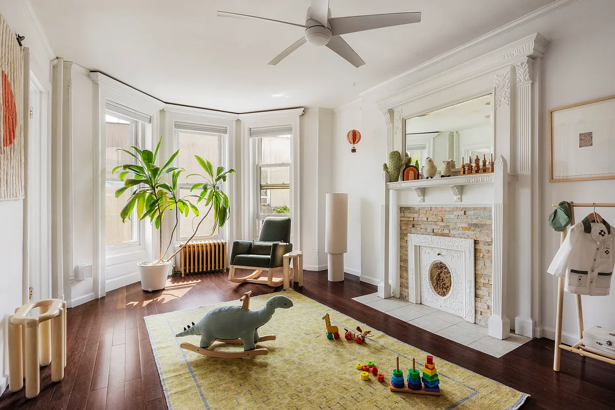 bedroom with white mantel, white walls, and ceiling fan