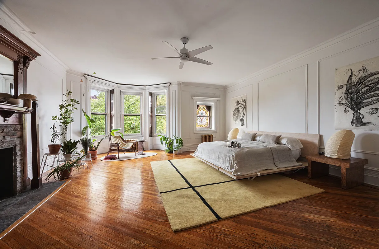 bedroom with stained glass window, wood floor, wood mantel