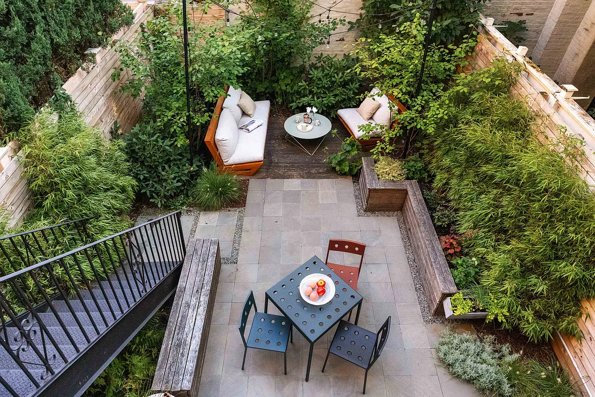 aerial view of landscaped rear yard with planting beds ringing the patio