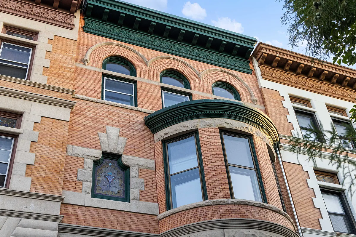brick row house with limestone details and a green painted cornice