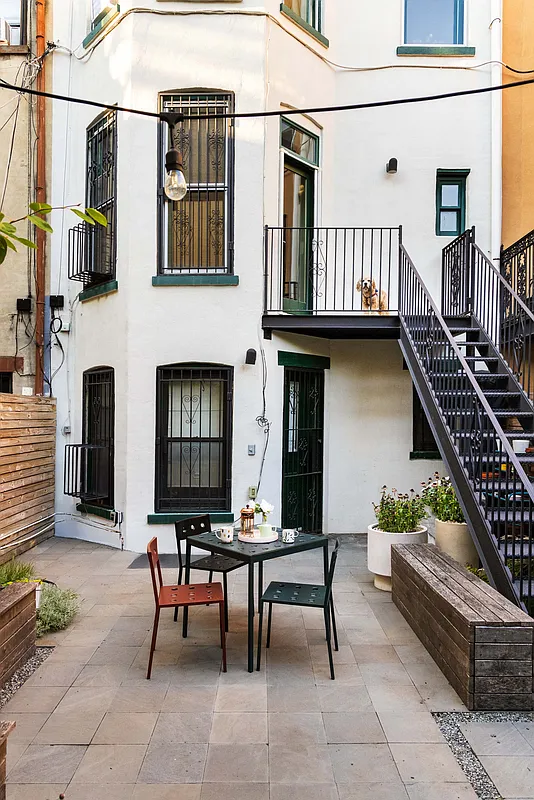 rear facade with iron staircase down to a paved patio