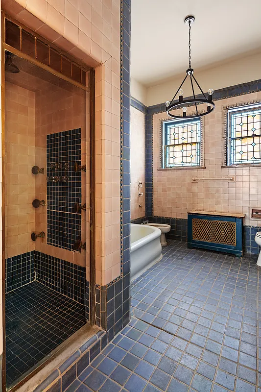 art deco bath with original black and pech tile, stained glass and built-in shower
