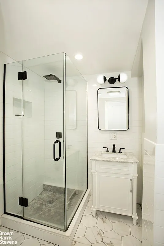 bathroom with glass doors around corner shower, white vanity