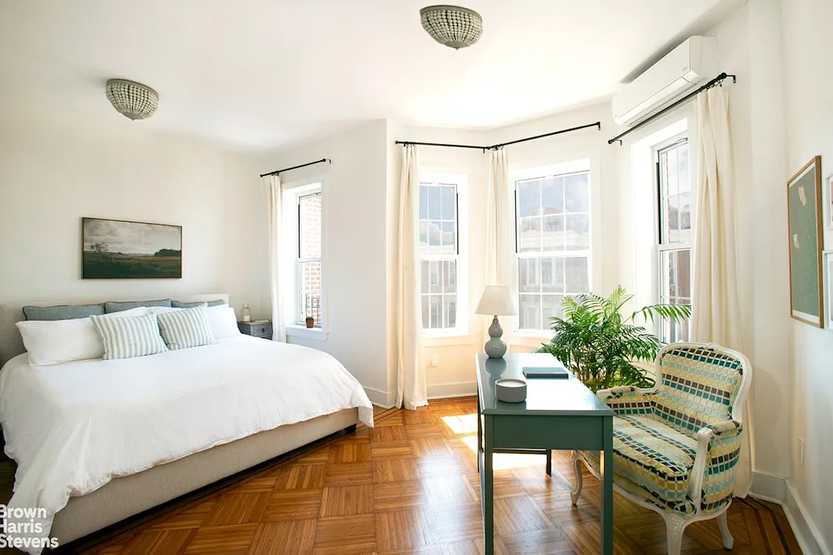 bedroom with wood floor, bay window, mini split