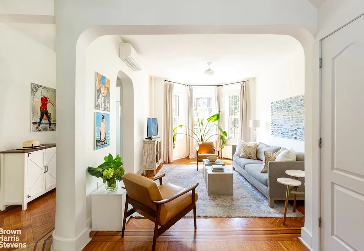 parlor with white walls, arched doorways, a mini split and wood floor