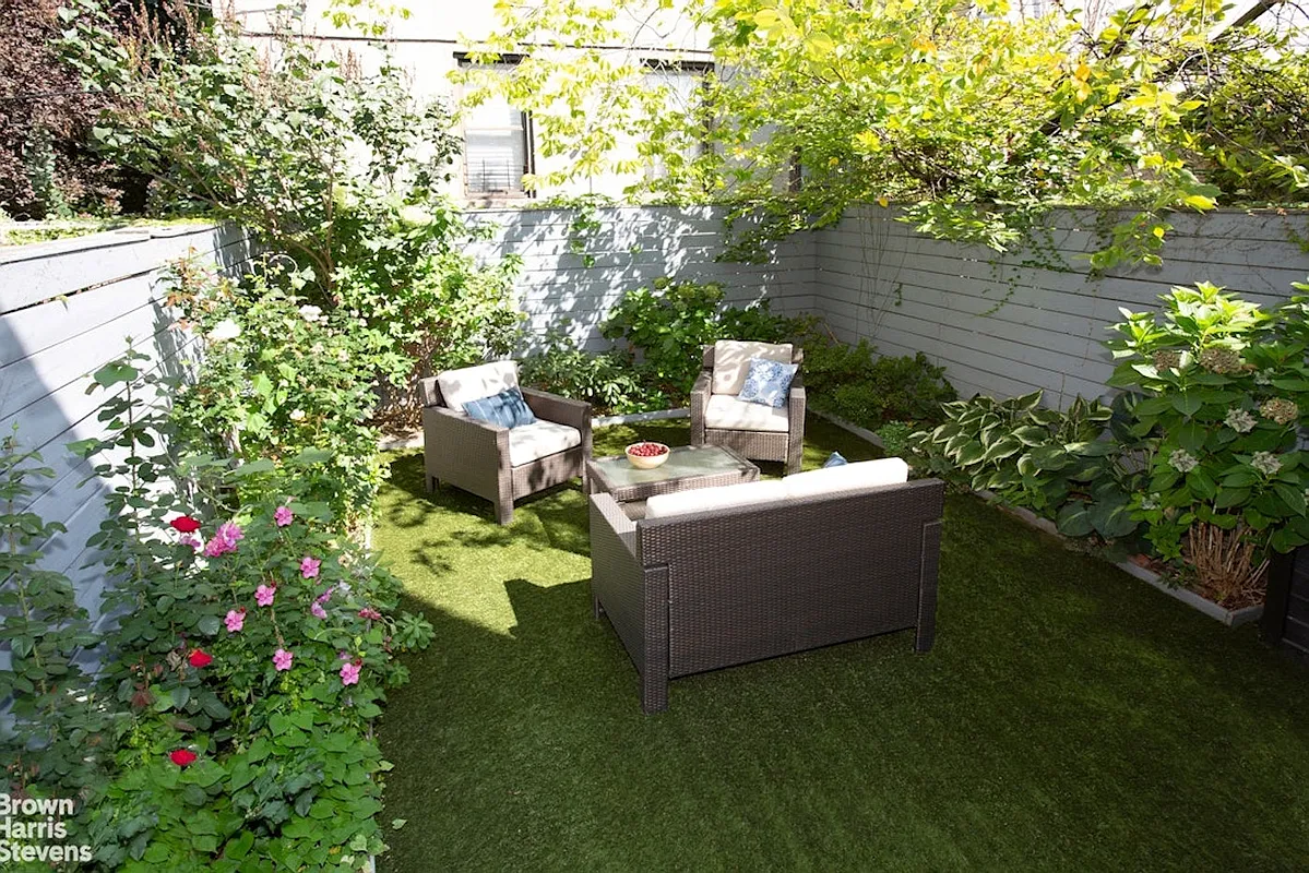 yard with a lawn ringed with planting beds and a horizontal fence