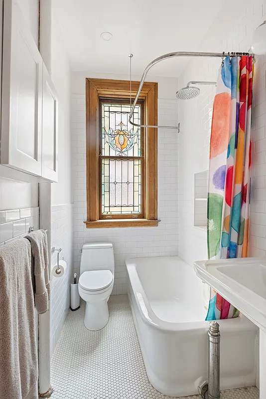bathroom with white fixtures and a stained glass window