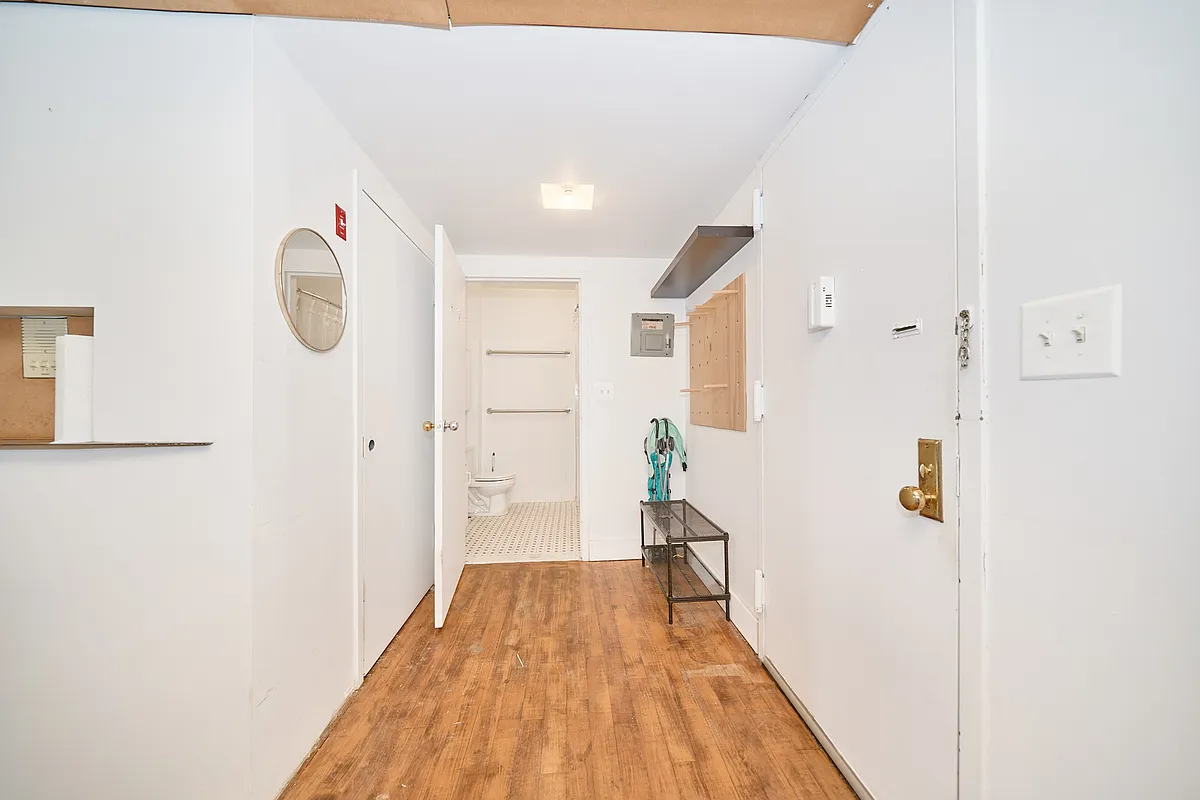 entry with wood floor, white walls and view of bathroom